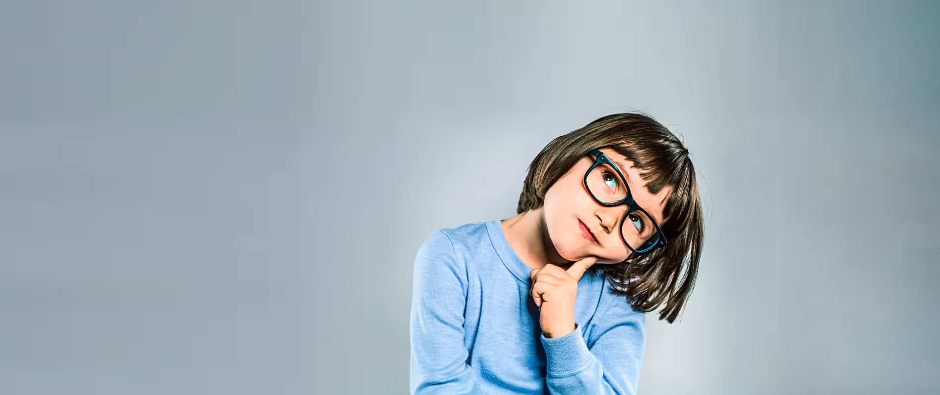 Kind mit Brille schaut nachdenklich zur Seite – Symbolbild für Sprachentwicklung und logopädische Förderung