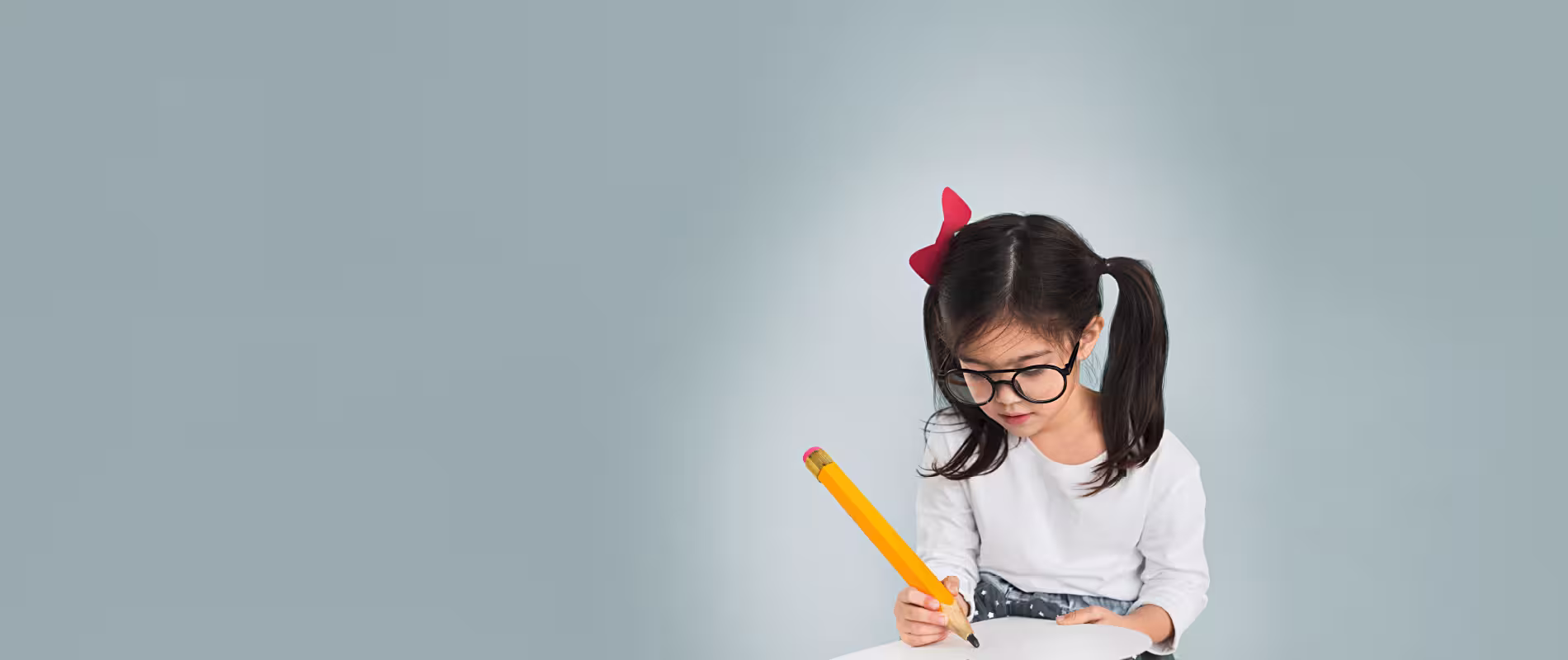 Kind mit Brille schreibt konzentriert mit großem Stift – Symbolbild für Lernen, Bildung und individuelle Förderung